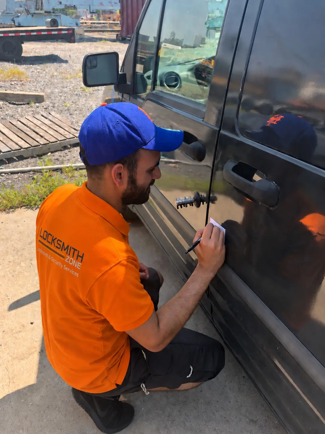 Yossi, owner of Locksmith Zone, in a branded shirt working on a vehicle door lock